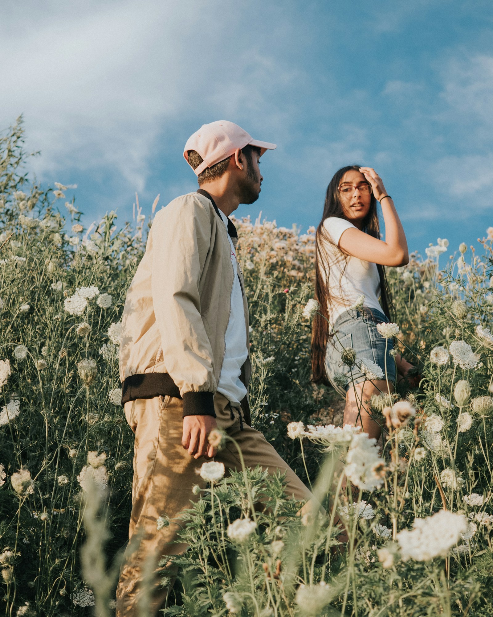 Two people walking through a wildflower field